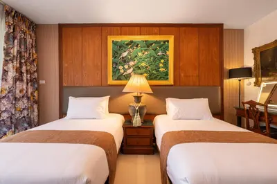 a hotel room with two beds and a table with a lamp at Star House Classic Style in Bangkok