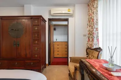 a bedroom with a dresser and a table and a chair at Star House Classic Style in Bangkok