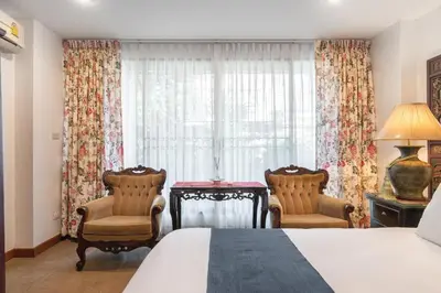 a bedroom with a bed and two chairs and a window at Star House Classic Style in Bangkok