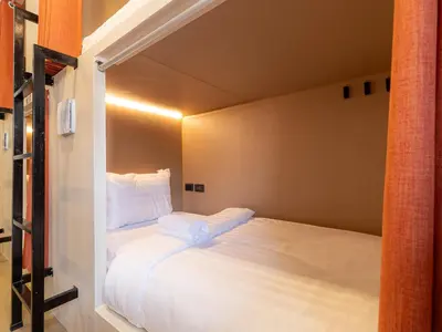 a small bedroom with a bed with white sheets and pillows at Social Pod Khao San Hostel in Bangkok