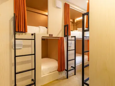 a room with four bunk beds with orange curtains at Social Pod Khao San Hostel in Bangkok