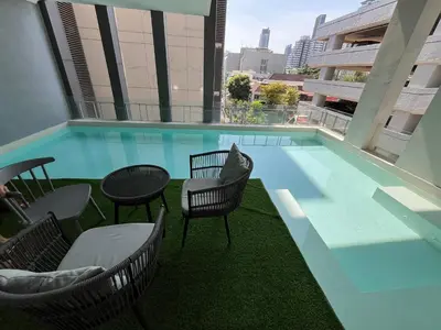 a swimming pool with chairs and tables on a building at Luxury Villa 4BR - 8 Mins to Thonglor BTS in Bangkok