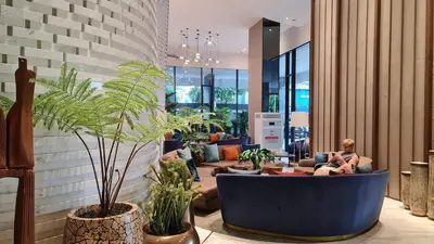 a man sitting on a couch in a room with plants at Perfect WFH 5 mins THONG LOR ultra luxury in Bangkok