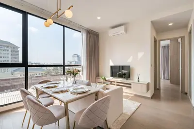 a living room with a table and chairs and a large window at Hampton Residence Phayathai in Sathani Sam Sen