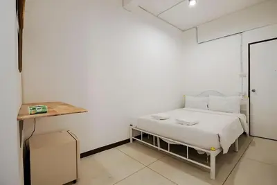 a white bedroom with a bed and a table at GO INN Asiatique - Riverfront Bang Kho Laem