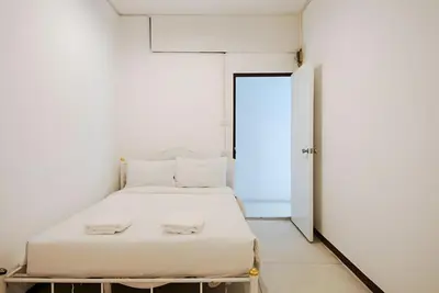 a white bed in a white room with a door at GO INN Asiatique - Riverfront Bang Kho Laem
