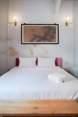 a bedroom with a white bed with a picture on the wall at Mitr Inn Yaowarat - เยาวราช Pro in Samphanthawong