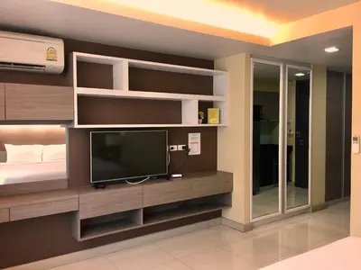 a room with a bed and a tv and shelves at Avatar Suites Hotel - SHA Extra Plus in Bangkok