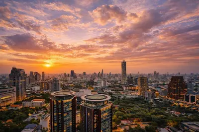 a city skyline at sunset with the sun setting at Luxe City Condo in Central Bangkok in Pratunam