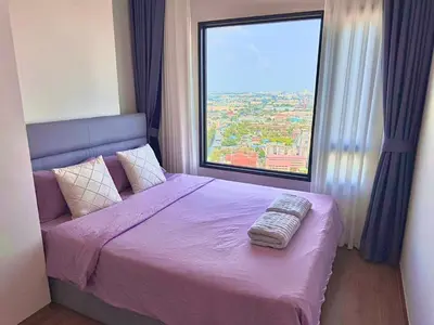 a bedroom with a purple bed with a large window at Bangkok Condo Ramkhamhaeng in Sathani Ban Hua Mak