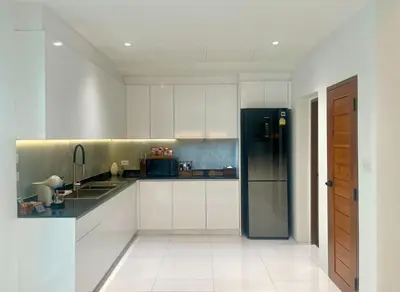a kitchen with white cabinets and a black refrigerator at Bhumidol Home near Don Muang Airport in Lak Si