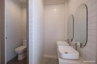 a bathroom with two sinks and a toilet and a mirror at Sadhu10BedBake in Bangkok