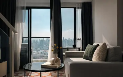 a living room with a couch and a glass table at High-Ceiling Loft Suite Rama 9 Design Apartment in Bangkok
