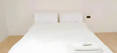 a white bed with a remote control on top of it at Snap Sukhumvit 1 - Bangkok City