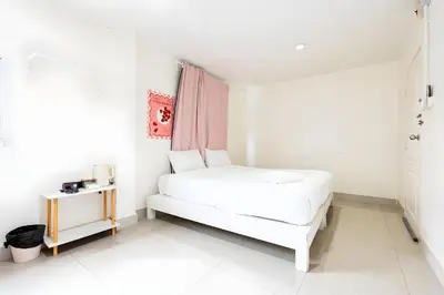 a white bedroom with a bed and a table at XX Oh My Nap Sukhumvit 3 - นานาเหนือ in Makkasan