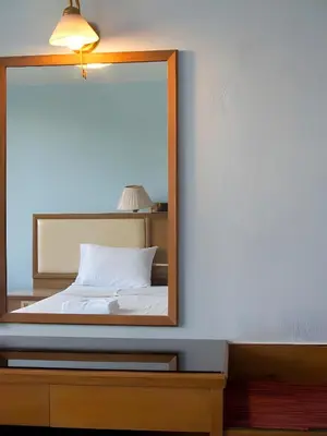 a mirror on a dresser next to a bed at Wish Inn Chidlom - Ratchadamri Bangkok in Pratunam