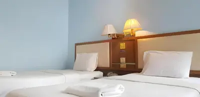 a room with three beds with white sheets and lamps at Wish Inn Chidlom - Ratchadamri Bangkok in Pratunam