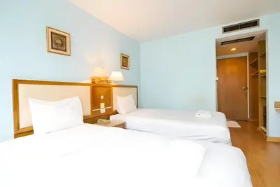 two beds in a hotel room with white sheets at Wish Inn Chidlom - Ratchadamri Bangkok in Pratunam