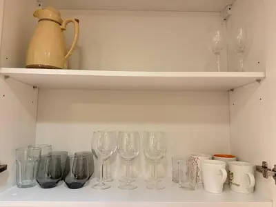 a row of wine glasses sitting on a shelf at Cozy City BTS Nana | Pool, Sauna & Gym 38th Floor in Makkasan