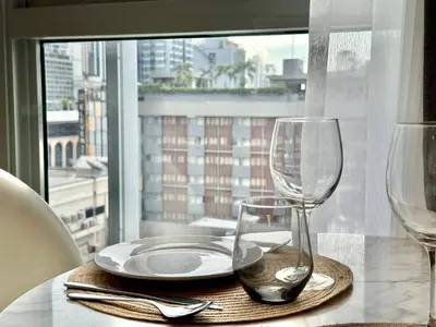 a table with a plate and two wine glasses at Cozy City BTS Nana | Pool, Sauna & Gym 38th Floor in Makkasan