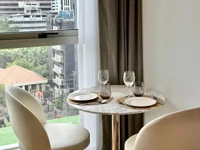 a table with glasses and chairs in front of a window at Cozy City BTS Nana | Pool, Sauna & Gym 38th Floor in Makkasan