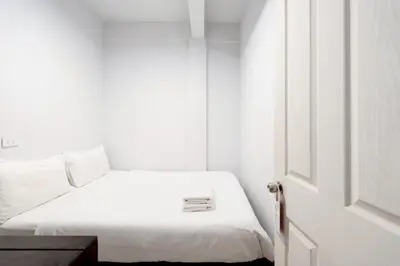a bedroom with a white bed with a white door at xx Mitr inn Khaosan ถนนตะนาว in Bangkok