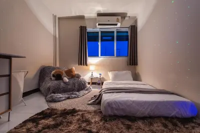 a bedroom with a bed and a chair and a window at High Friend Hostel in Phra Khanong
