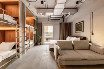 a hotel room with bunk beds and a couch at The District Hostel Ekkamai in Sathani Khlong Tan