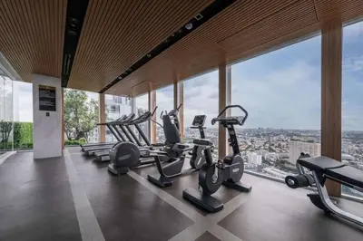 a gym with cardio equipment in a building with windows at Sky Luxury Near BTS Ekkamai pool gym Netflix in Khlong Toei