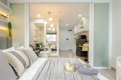 a living room with a white couch and a kitchen at 1 BR 5 Mins BTS Bearing 7-11 and Lotus in Ban Khlong Samrong