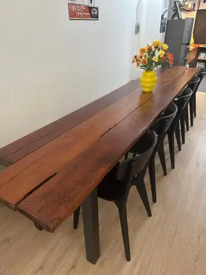 a large wooden table with chairs and a vase of flowers at Sleepben in Bangkok
