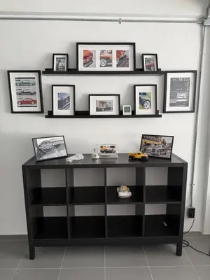 a black shelf with pictures on a wall at Sleepben in Bangkok
