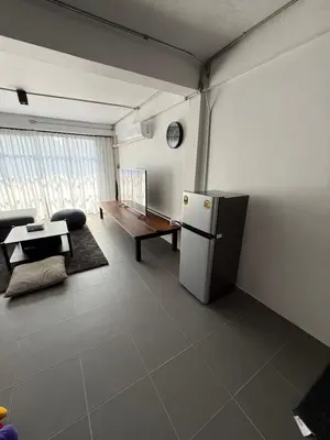 a living room with a refrigerator and a table at Sleepben in Bangkok
