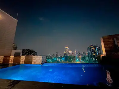 a blue swimming pool with a city skyline at night at Luxury Apt BTS EKKAMAI with pool sauna gym in Bangkok