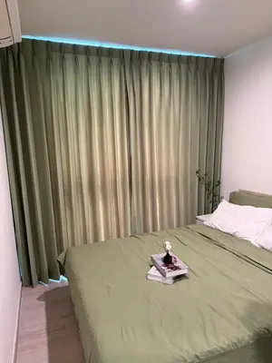 a bedroom with a bed with a green blanket at Quiet apartment with pool close to MRT station in Bangna