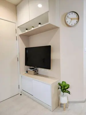 a living room with a tv and a clock on a wall at Homely Condo Minimal Style Near BTS Silom line in Bang Khun Thian