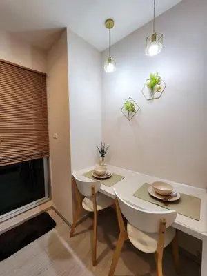 a dining room with a white table and a tv at Homely Condo Minimal Style Near BTS Silom line in Bang Khun Thian