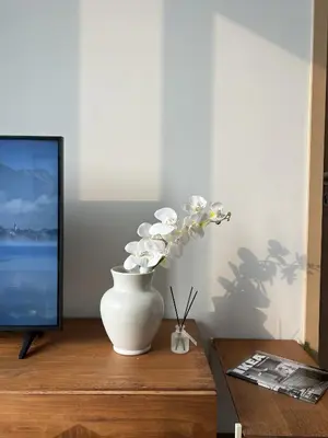 a white vase with white flowers in it on a table at WalkToBTS>EMDistrict/CityViewPool&Gym/WiFi/Washer in Khlong Toei