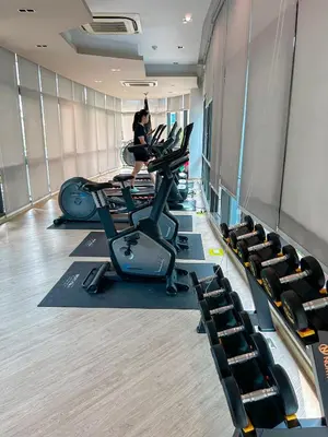 a gym with rows of treadmills and a woman on a treadmill at Luxury apartment near On Nut BTS station with swimming pool in Amphoe Phra Khanong