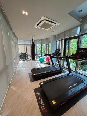 a gym with treadmills and ellipticals in a room with windows at Luxury apartment near On Nut BTS station with swimming pool in Amphoe Phra Khanong