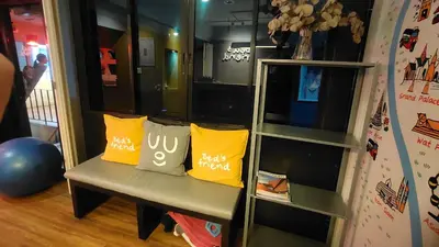 a bench with yellow pillows on it in a room at Bed's Friend in Bangkok