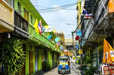 a bus driving down a street with buildings and flags at The Backpack Hostel in Bangkok