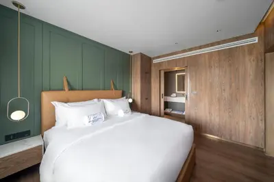 a bedroom with a large white bed and green walls at Maison Hotel Bangkok in Bangkok