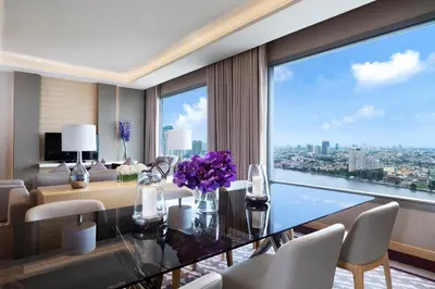 a dining room with a table and a large window at Avani Plus Riverside Bangkok Hotel in Bangkok