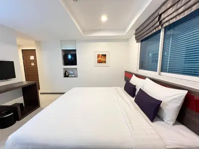 a bedroom with a large white bed and a window at Cubic Pratunam in Bangkok
