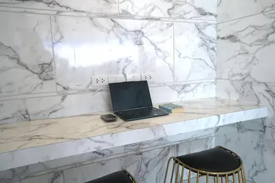a laptop sitting on a marble counter with two chairs at Cubic Pratunam in Bangkok