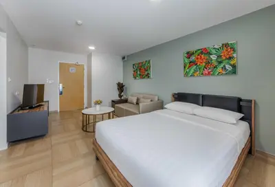 a bedroom with a large bed and a living room at Chiva Bangkok Hotel in Bangkok