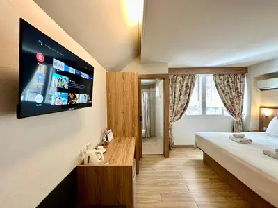a hotel room with a bed and a flat screen tv at Dinsomon Hotel in Bangkok
