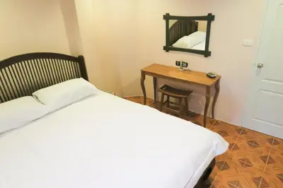 a bedroom with a bed and a table with a mirror at The Grand Palace Hotel in Bangkok