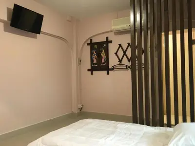 a bedroom with a bed and a tv on the wall at The Grand Palace Hotel in Bangkok